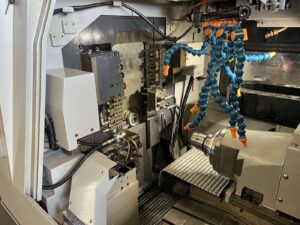 Swiss lathe turning machine including a chuck and multiple coolant lines.